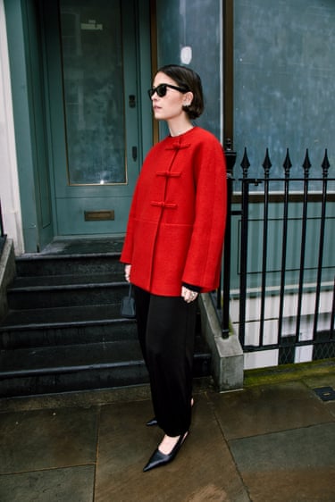 A person wearing a red jacket and black trousers