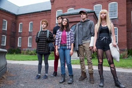 five people stand next to each other in front of a building