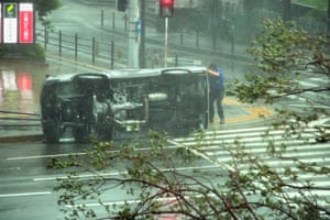 A man stands alongside an overturned car in Osaka