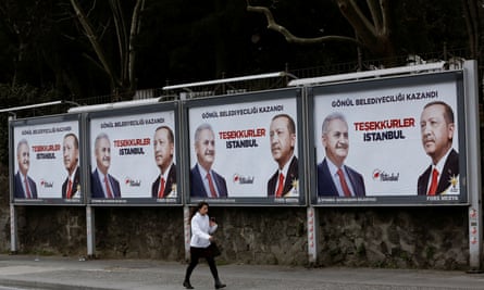 A woman walks past AKP billboards in Istanbull thanking voters featuring Erdoğan and mayoral candidate Binali Yıldırım