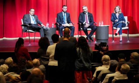 four people sit on stage and listen to an audience member