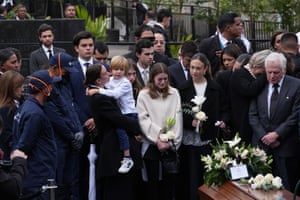 Devastated family stood next to a coffin in a cemetery