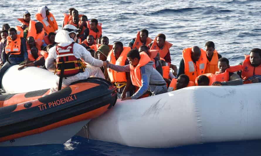 People are helped into a small rescue boat in the Mediterranean Sea