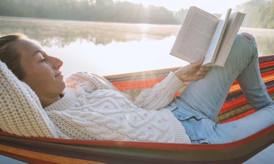 Young woman relaxing on hammock with a book
