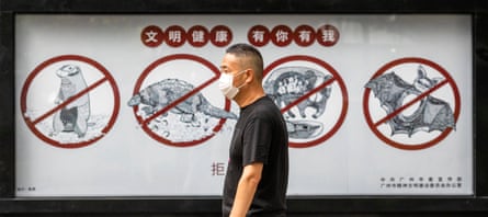A man walks past a poster warning people in Guangdong province, China, that consuming wildlife is illegal.