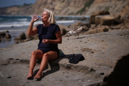 a women drinking water next to a bird
