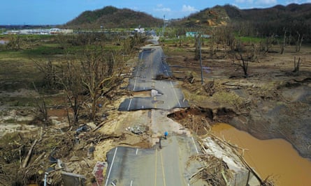 A man rides his bicycle through a damaged road, following the passage of Hurricane Maria.