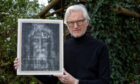 David Rolfe, dressed in black, holds up a negative image of the face on the Turin Shroud