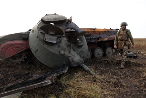 A Ukrainian soldier walks past a destroyed Russian tank on the front line in Donetsk.
