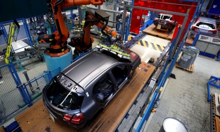 A half-finished vehicle standing in a bay surrounded by machine tools, viewed from above
