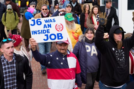 People gather and hold signs, one of which says 'J6 Was an Inside Job'.