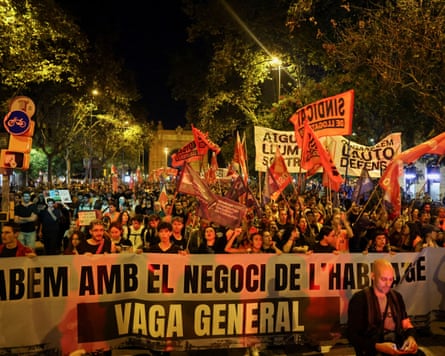 A night shot of a large crowd of people with those at the front holding a large banner