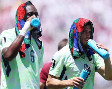 Swiss footballers Denis Zakaria and Remo Freuler take a drink with towels over their heads during a hydration break at the World Cup