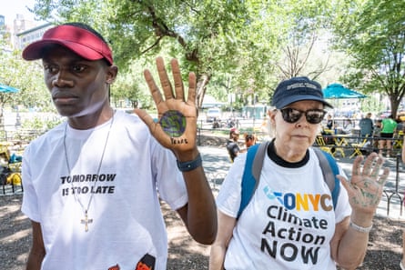 Climate activist Nyombi Morris displaying a number 5 on his palm, with an associate demanding action on the climate.
