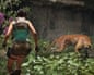 Lara Croft crouches with two pistols, facing a growling leopard in dense jungle foliage