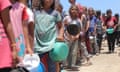 A line of young Palestinians wait with empty food bowls