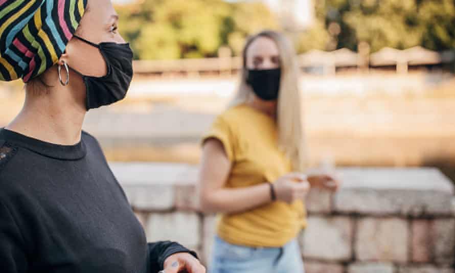 Δύο γυναίκες με μάσκες προσώπου μιλούν σε κοντινή απόσταση με τα πόδια.