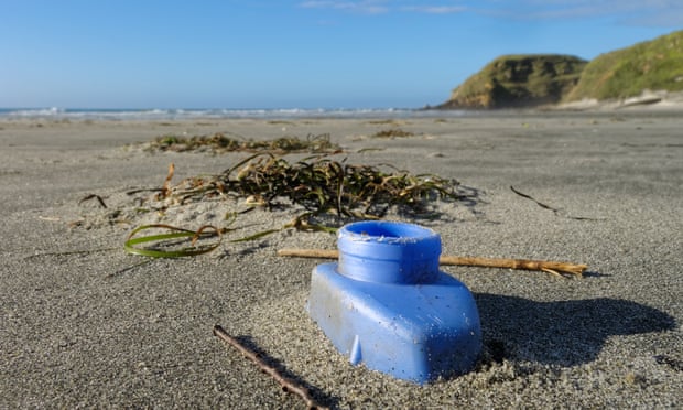 Discarded blue plastic bottle part buried on a beach on New Zealand's west coast. A deathtrap for small creatures.