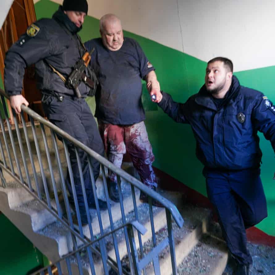 Ukrainian security forces help a wounded man downstairs