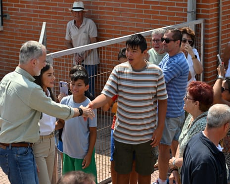 O rei Felipe e a rainha Letizia da Espanha apertam a mão das pessoas enquanto visitam os evacuados do incêndio florestal em Madri que estão alojados no centro esportivo local em Villamanta
