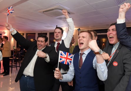 Four men in suits wave union flags and punch the air