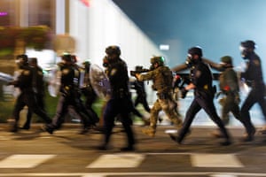 Police with shields charge in a group across a zebra crossing at dawn