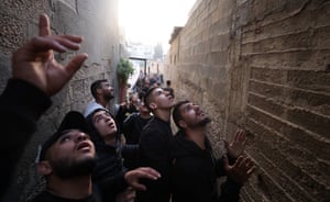 Palestinians in narrow alleyway peer upwards