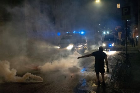 Protester silhouetted against clouds of teargas on street at night