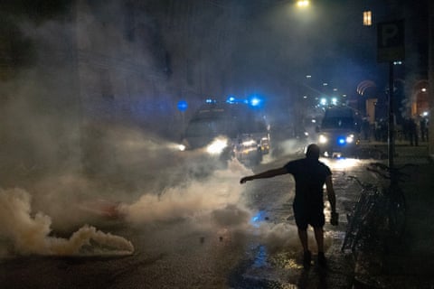 Protester silhouetted against clouds of teargas on street at night dqxikeidqkiehinv