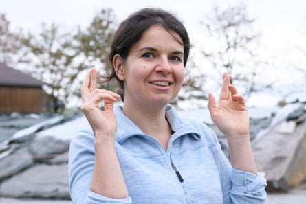 A woman smiles at the camera and holds up her hands with her fingers crossed