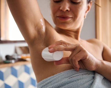 A woman applying deodorant in a bathroom after showering