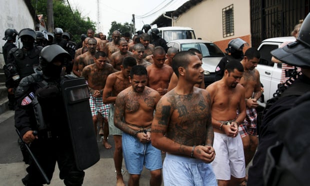 Gang members are guarded by policemen upon their arrival at a prison in El Salvador on 29 March 2016. 
