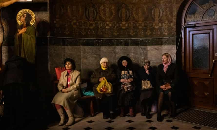 People sitting on bench in church, with women wearing headscarves.