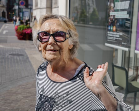An older woman on the street wearing designer sunglasses and carrying a bag over her shoulder