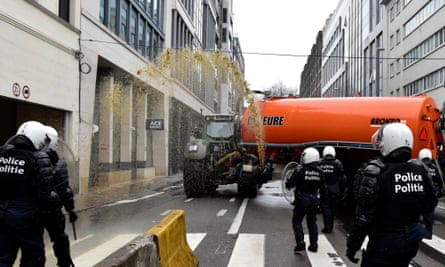 A farmer spraying manure at riot police in Brussels