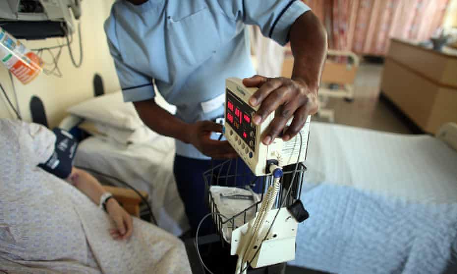 A nurse tends to patients on a general ward