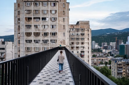 A young woman walks along one of the bridges connecting the three tall Soviet-era buildings on Nutsubidze Street in Tblisi