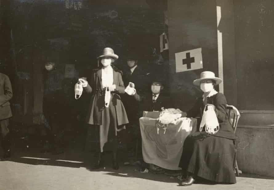 I volontari della Croce Rossa distribuiscono maschere antinfluenzali a un tavolo a San Francisco nel 1918.