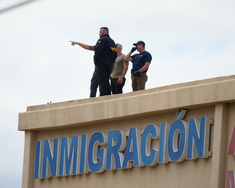 people stand on the roof of a building and point