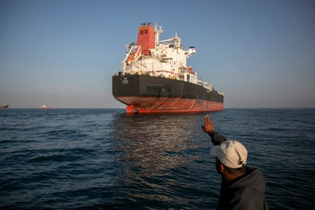 A man waves at a large cargo ship