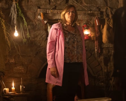 Liza Tarbuck stands in a cave lit with candles, looking baffled