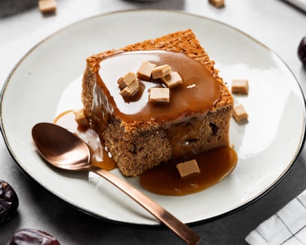 A photograph of sticky toffee pudding on a white plate, with toffee sauce poured over the top.