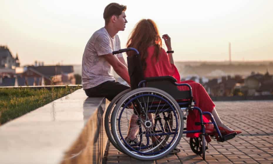 Young man sitting next to young woman in wheel chair