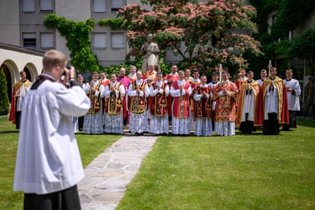 Newly ordained priests and deacons in garden wearing red vestments