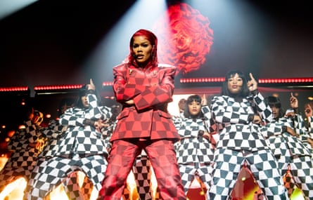 Taylor on stage in a red suit flanked by backup dancers in black and white suits.