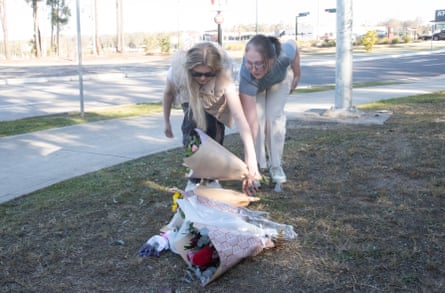 Georgia Bainbridge and her friend lay floral tributes near a roadblock on Wine Country Drive near Branxton in the Hunter Valley