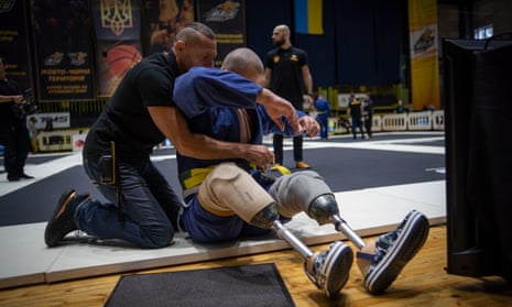 26-year-old Vasyl Oksyntiuk, right, Ukrainian war veteran receives help of tying the belt of his kimono during Ukrainian national competition of jiu jitsu in Kyiv, Ukraine, Sunday, Oct. 29, 2023.