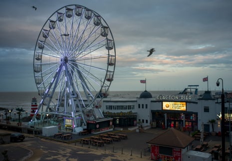 A ferris wheel by a fish’n’ chip outlet at the entrance to a Victorian seaside pier. A sign says “winner of the best family attraction in Essex 2024!”