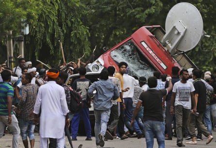 Sect members overturn an outside broadcast van in Panchkula during deadly riots.