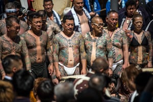 Heavily tattooed Japanese men and a woman pose for photographs near Asakusa Temple